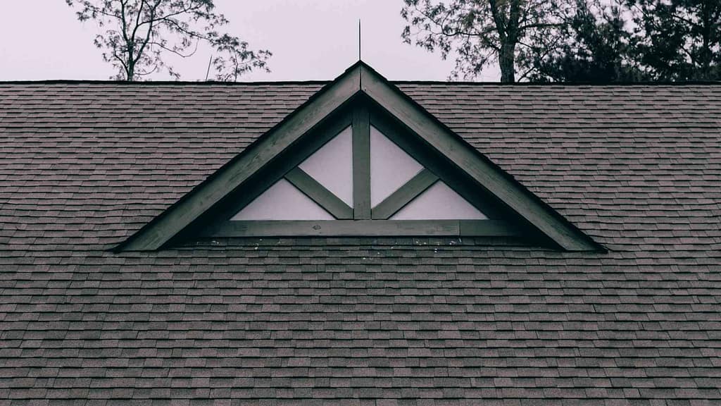 Triangular window on the roof of a house with white panes.