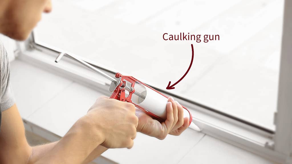 Person using caulking gun to seal window