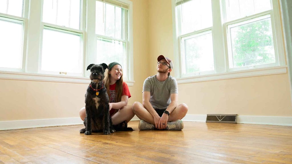 Happy couple with their mutt sitting on the floor of their home