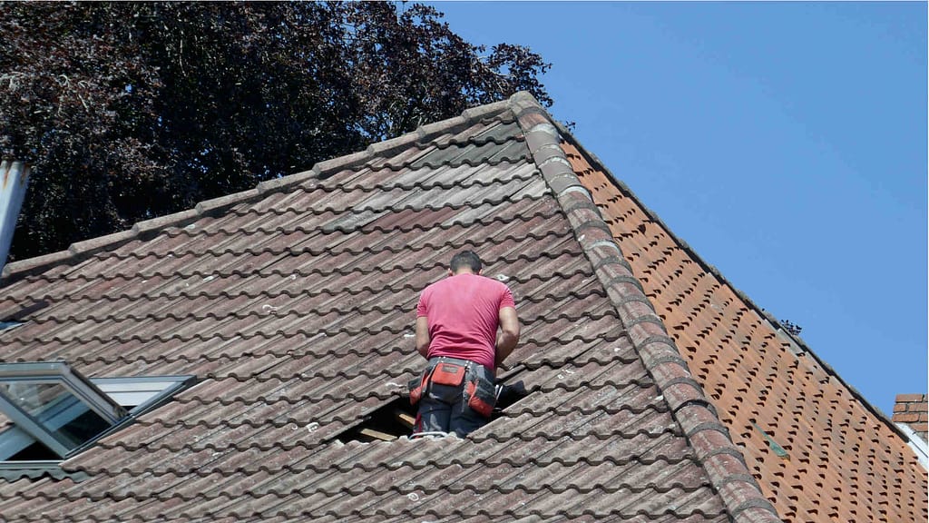 Person repairing hole in a tile roof