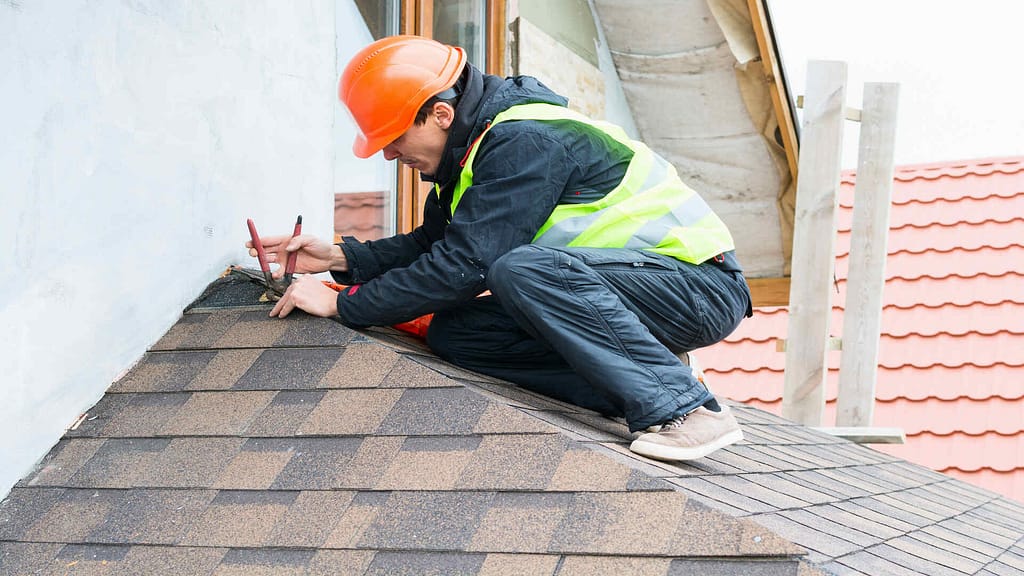 Roofer repairing roof shingles